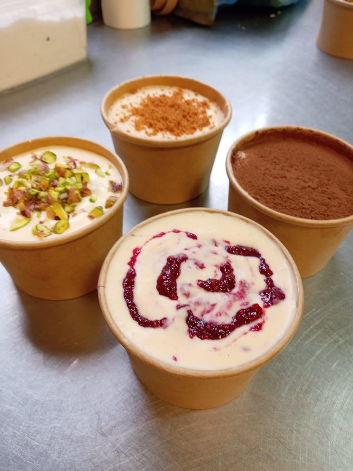 Cuatro porciones de tiramisú Ophelia en vasos de kraft: pistacho, Biscoff, clásico y frambuesa